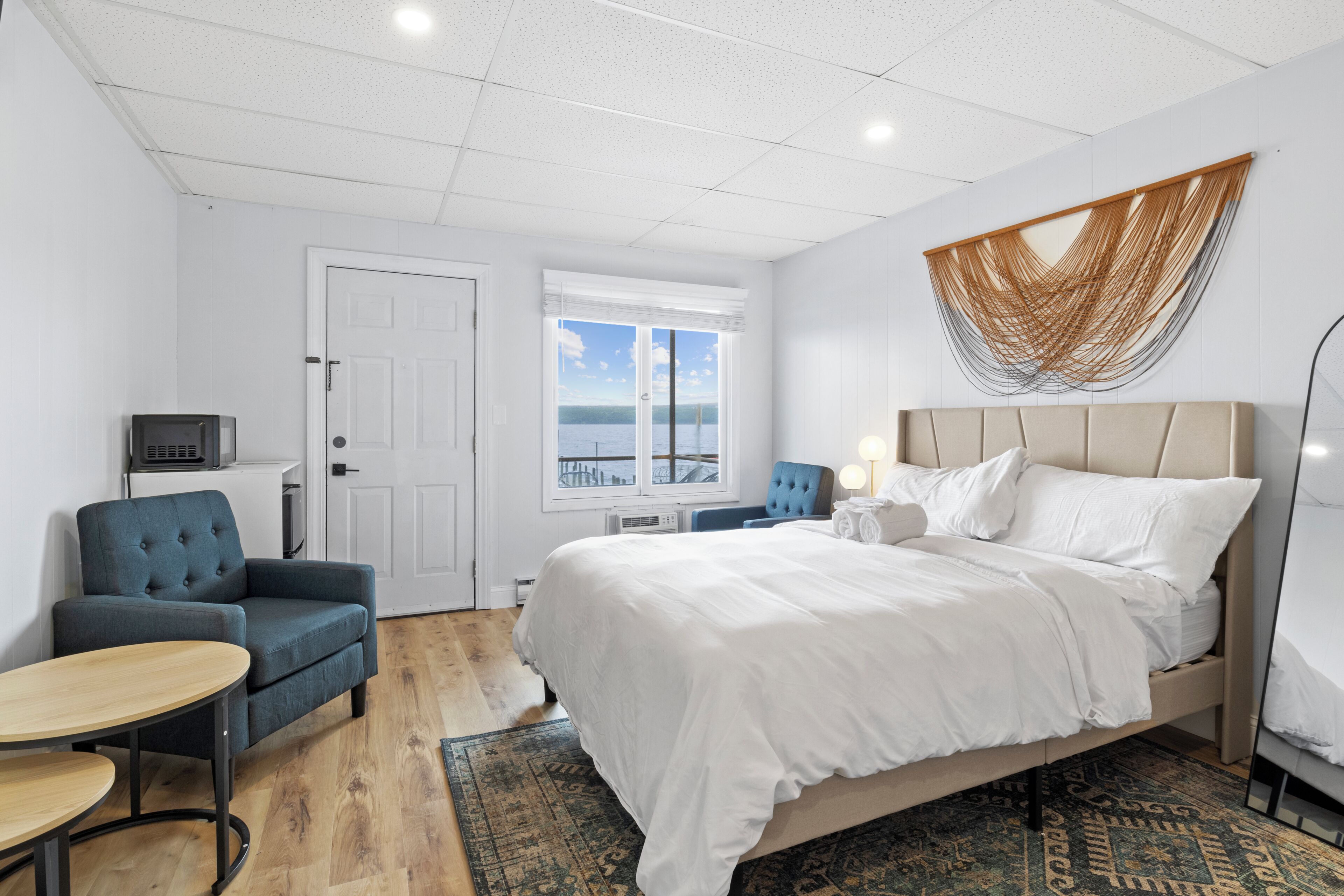 Une chambre d’hôtel avec un lit, une chaise, une table, un téléviseur et une vue sur la mer.