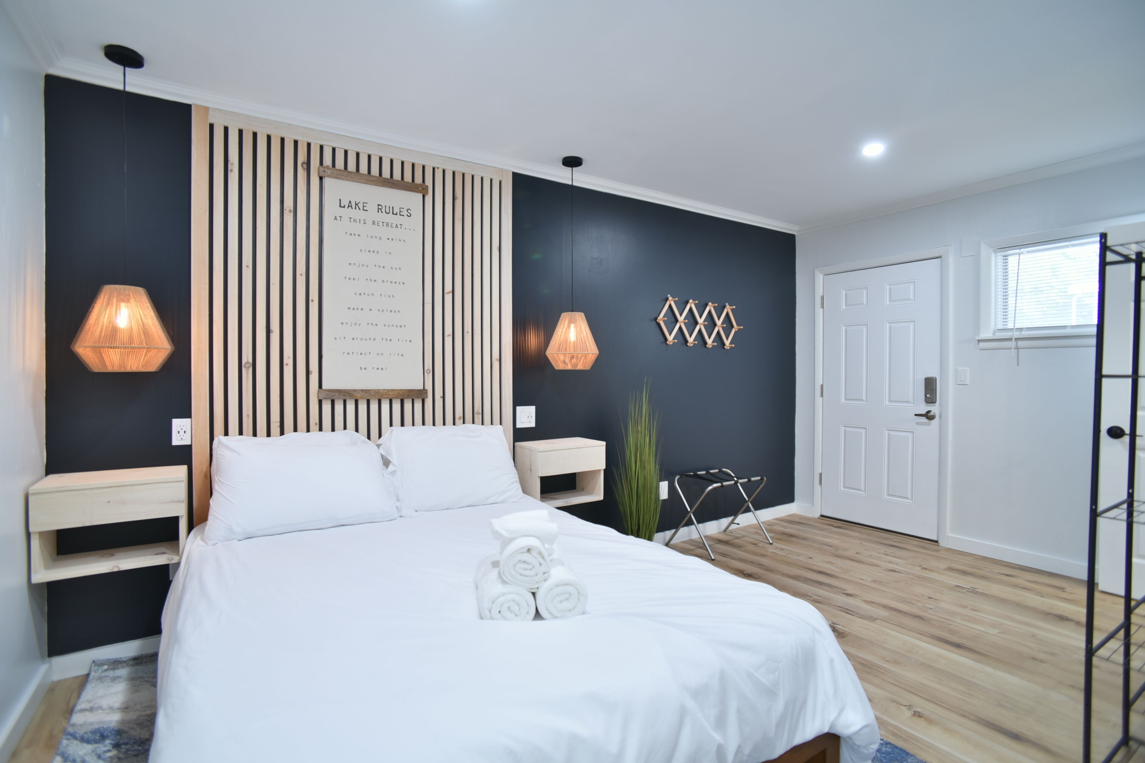 A modern bedroom with a bed, a wall-mounted light, a wooden panel, and a door.