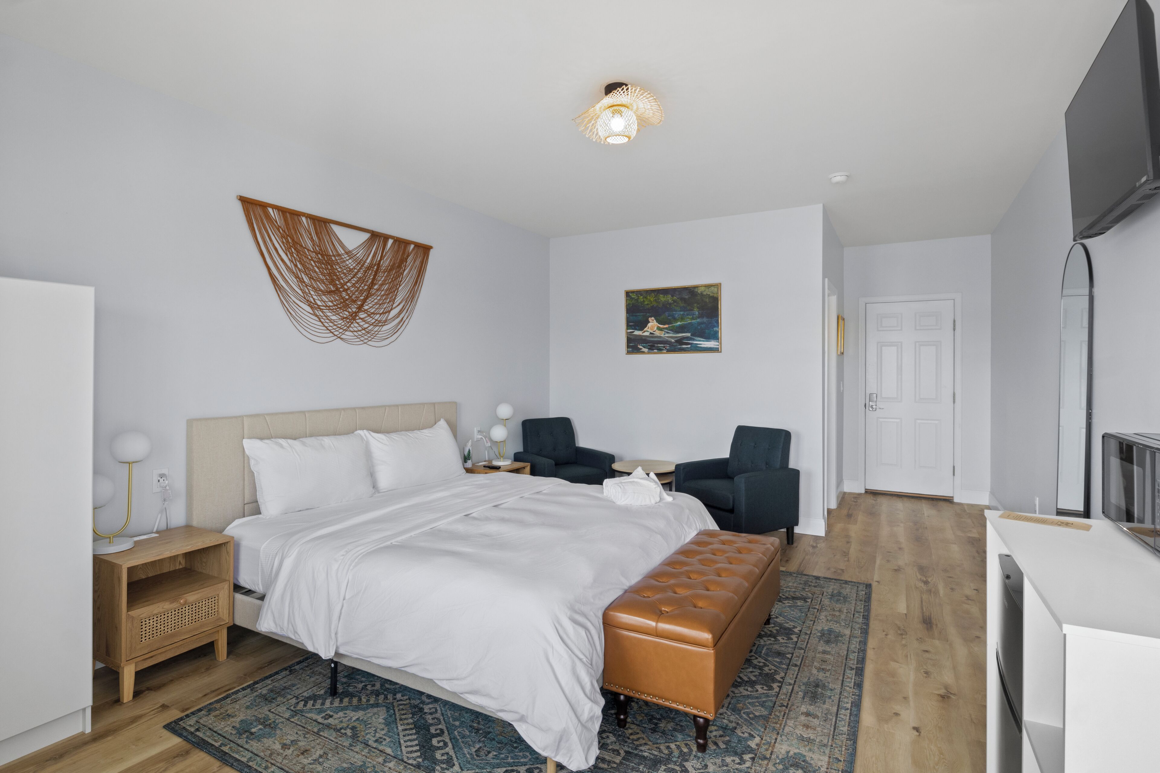 A modern hotel room with a bed, seating area, and a television.