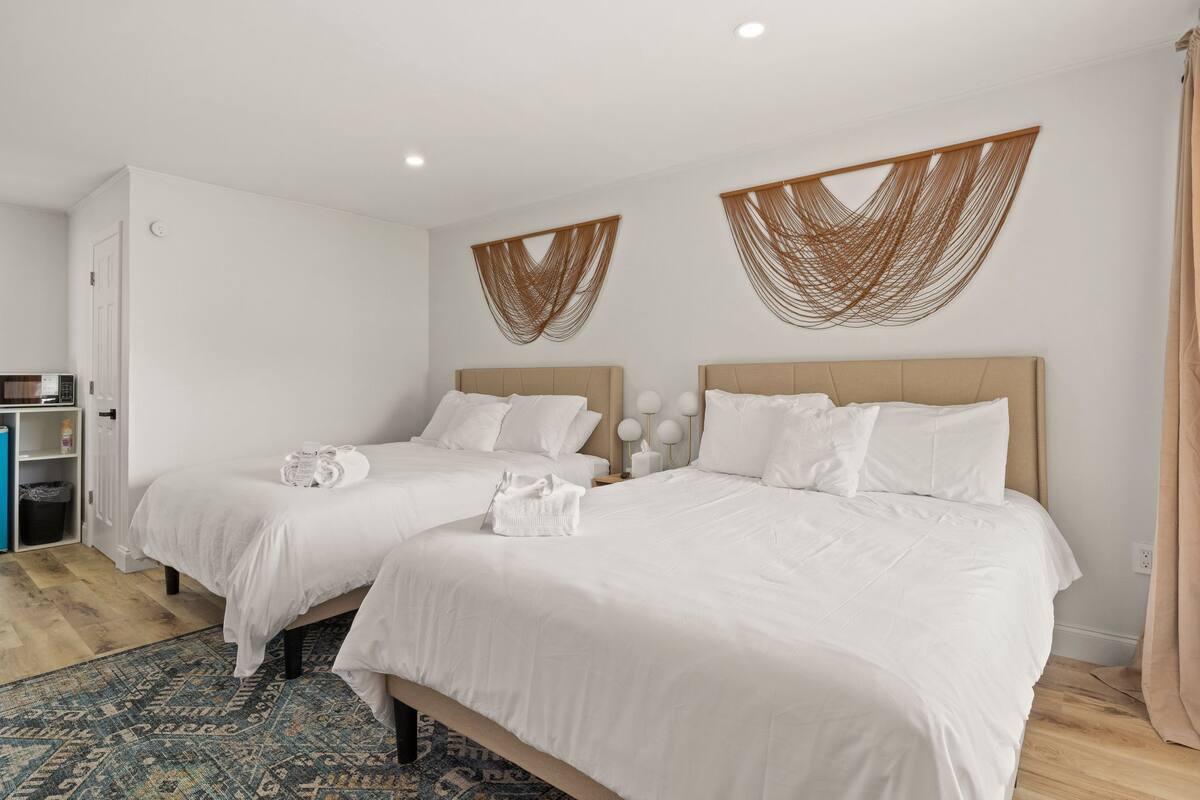 Una habitación de hotel con dos camas, un minibar y una alfombra estampada.