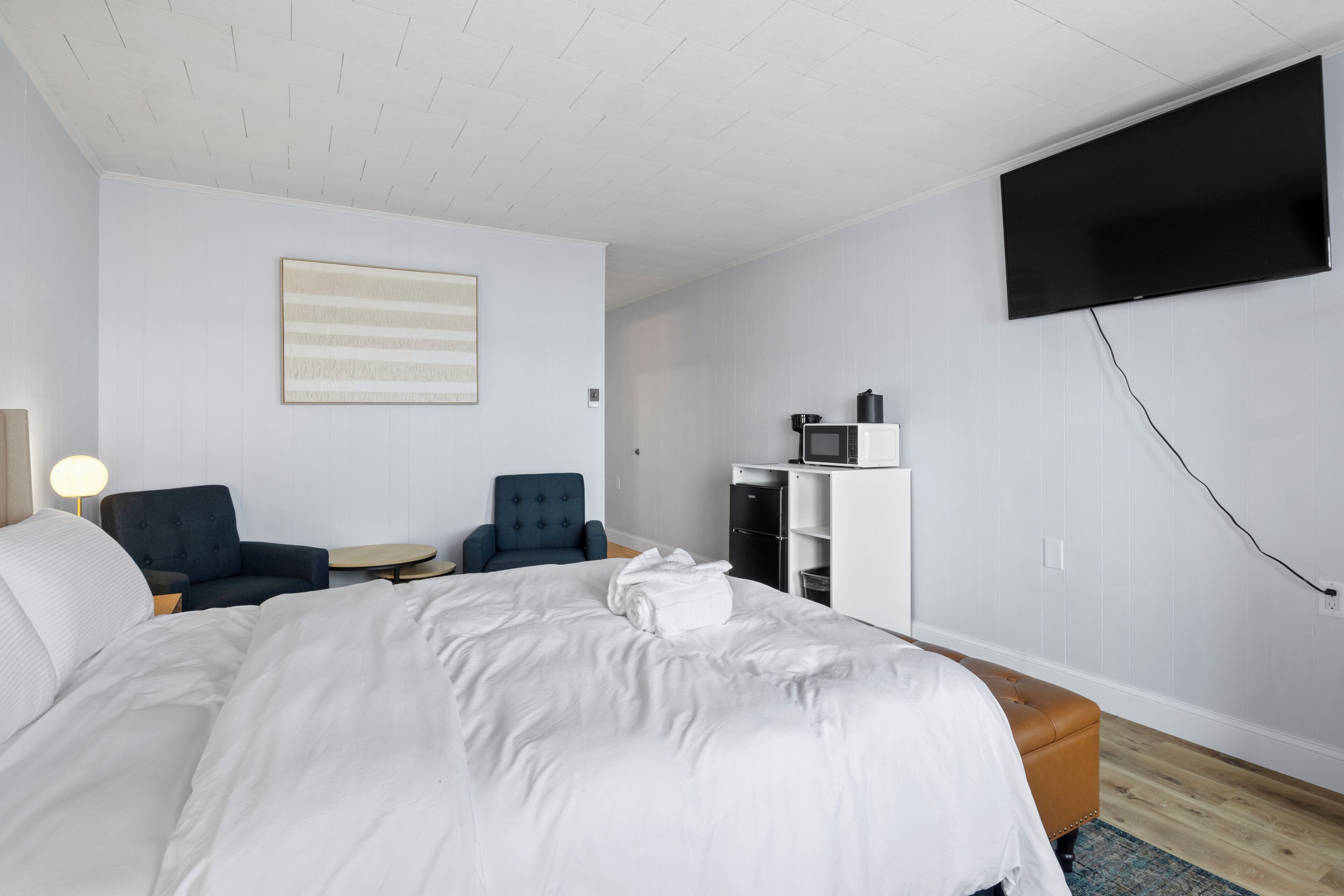 Una habitación de hotel con una cama grande, dos sillones, un escritorio, un televisor de pantalla plana y un microondas.