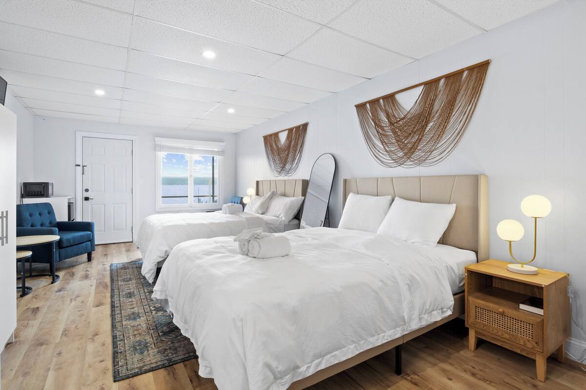 Habitación de hotel moderna con dos camas, un escritorio, una silla y vista al mar.