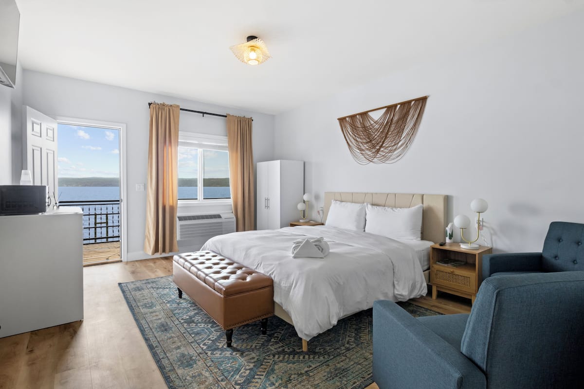 Habitación de hotel con cama, zona de estar, escritorio y vista al mar.