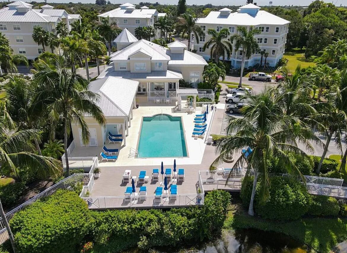 A resort with a central pool, lounge chairs, and palm trees.