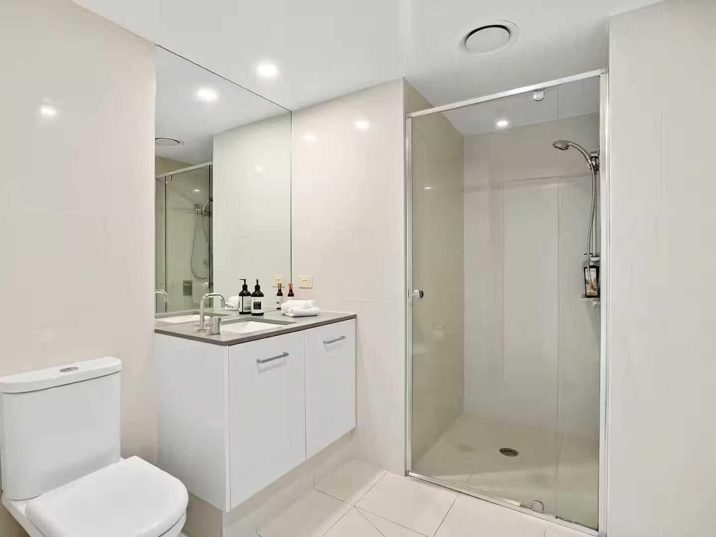 A modern bathroom with a toilet, sink, and shower.