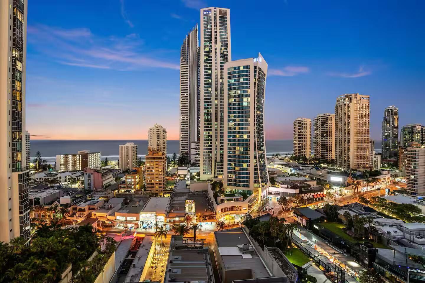 A cityscape with high-rise buildings, a waterfront, and a well-lit urban area.