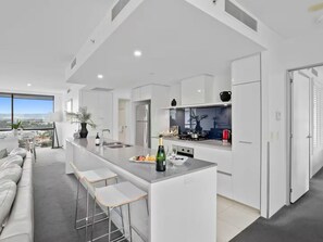 Een moderne keuken met een centraal eiland, barstoelen en uitzicht op de stad.