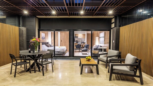 Un hall d’hôtel moderne avec une table de salle à manger ronde, des sièges et une vue sur la cuisine.