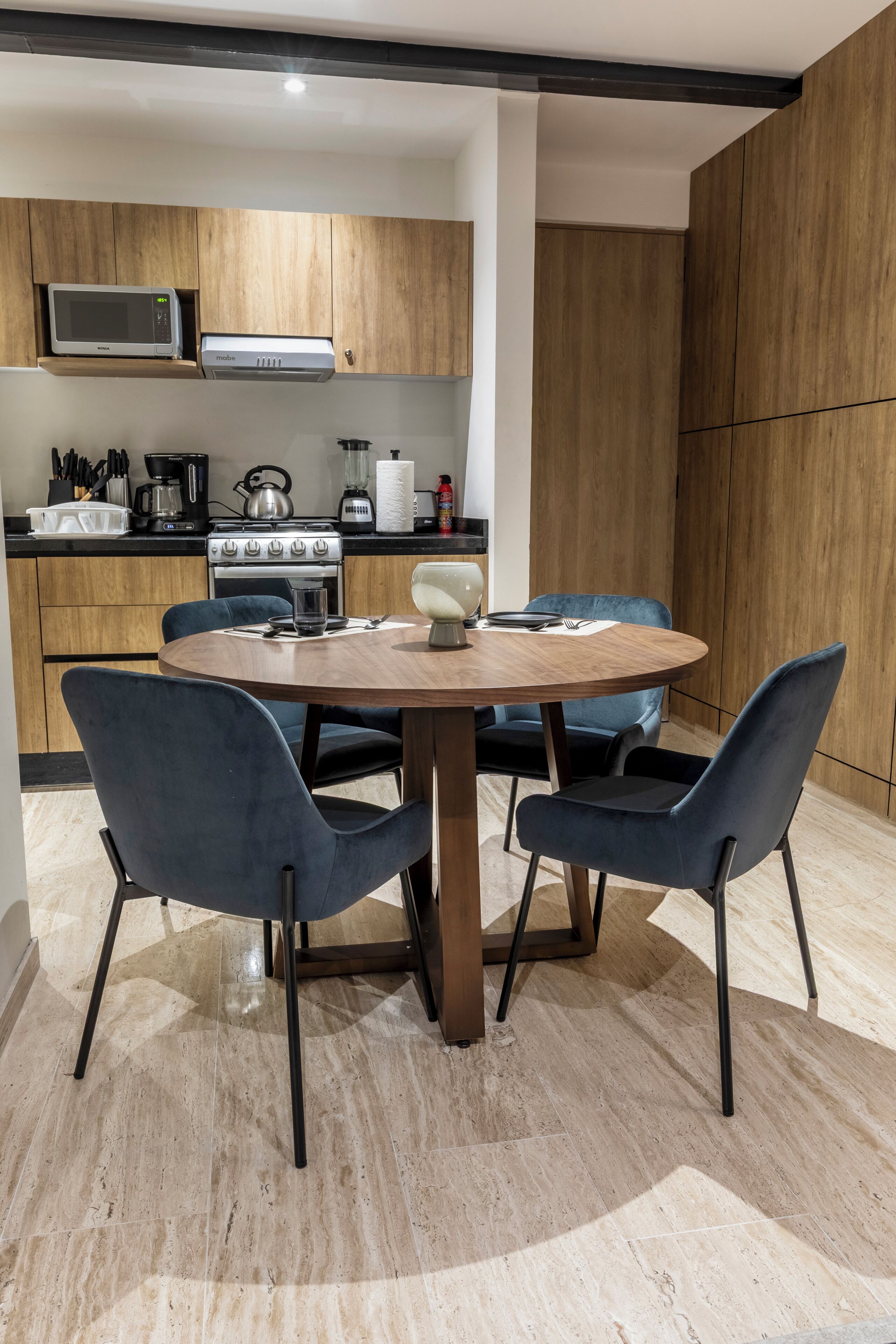 Une cuisine moderne avec des meubles en bois, un four à micro-ondes, une cuisinière et un coin repas comprenant une table ronde et des chaises.