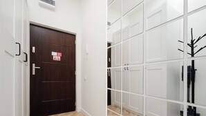 Ein Korridor mit einer Holztür, einer weißen Wand mit Telefon und einem Spiegelkleiderschrank mit Kleiderhaken.