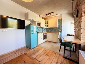 Eine kompakte Küche mit integriertem Mikrowellenherd, einem Kühlschrank und einem Essbereich mit Tisch und Stühlen.