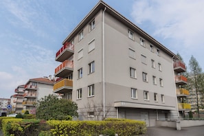 Un immeuble résidentiel à plusieurs étages, doté de balcons, avec une porte de garage bien visible et un ciel dégagé.