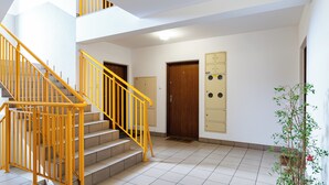 Eine Treppe mit gelb gestrichenen Geländern, eine Holztür, eine Wandtafel und ein Blumentopf.