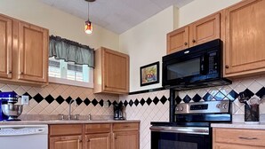 Cozinha com armários de madeira, micro-ondas, forno e lava-louças.