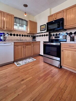 A kitchen with wooden cabinets, a microwave, an oven, and a dishwasher. - Charming  Covington House. (Covington)