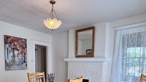 Uma sala de jantar com lareira branca, um espelho grande e um tapete floral.