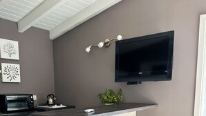 A modern kitchen with a built-in island, a microwave, a kettle, and a flat-screen TV mounted on the wall. - Botanical Study 1 (San Carlos de Bariloche)