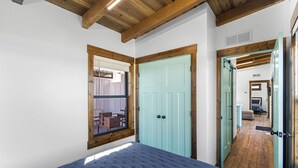 Un dormitorio con cama, ventana, puerta y pasillo que conduce a otra habitación.