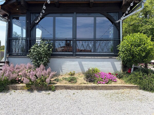 Un bâtiment doté d’un balcon, de grandes fenêtres et d’un jardin de gravier agrémenté de différentes plantes.