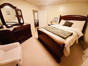 Une chambre à coucher avec un lit en bois, une commode, un miroir et une table de chevet avec une lampe.