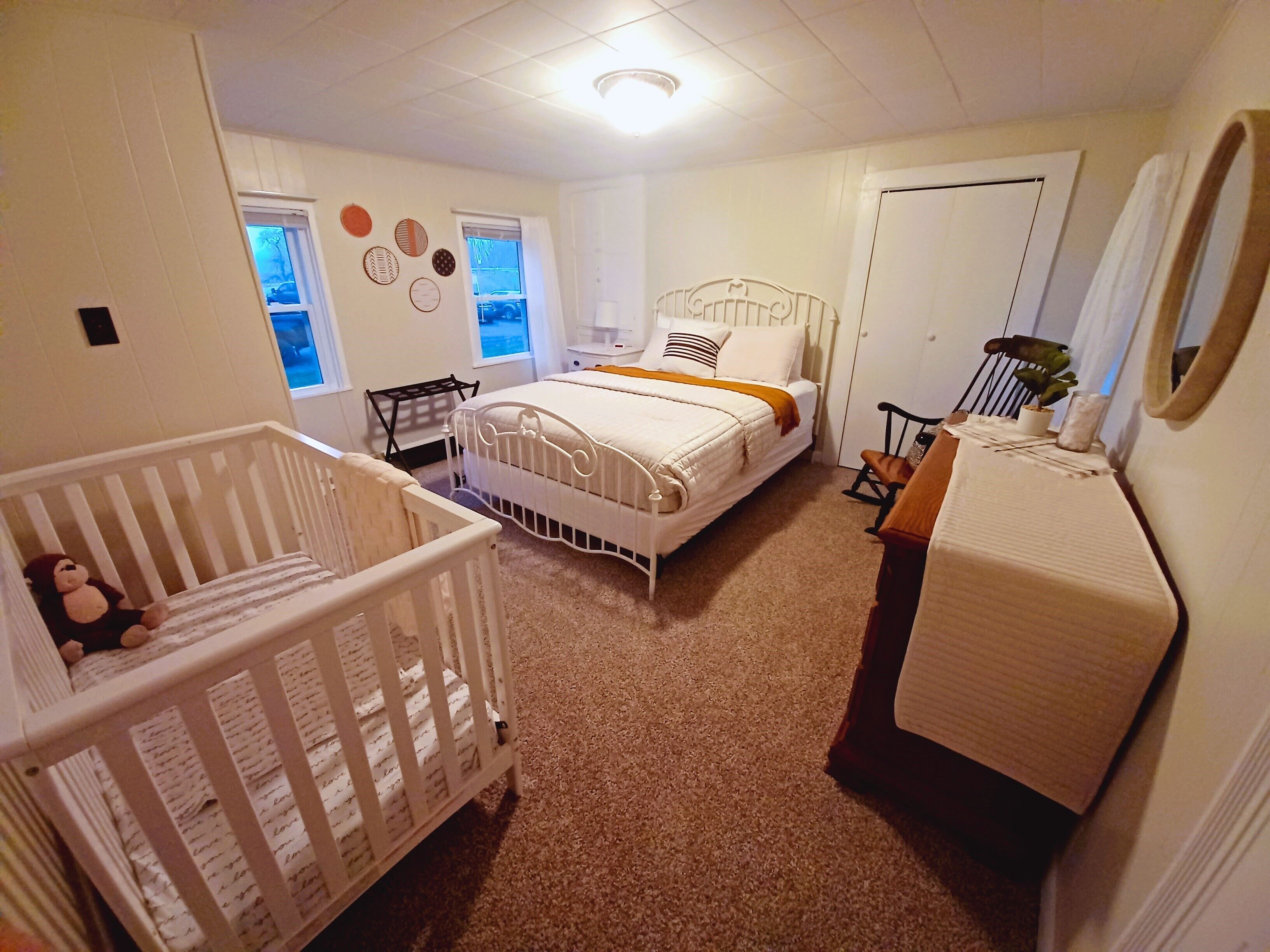 Ein Babyzimmer mit einem Kinderbett, einem Bett, einer Wickelkommode und einer Kommode.