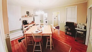 Une cuisine équipée d’une table à manger, de chaises, d’une machine à café et d’un transat pour bébé.
