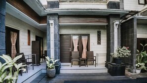 A poolside area with a seating arrangement, a door with curtains, and potted plants. - Denays Guest House Jimbaran (Jimbaran)