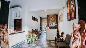 A reception area with a reception desk, seating, and decorative statues. - Denays Guest House Jimbaran (Jimbaran)