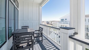 Ein Balkon mit Tisch und Stühlen, weißen Geländern und Blick auf andere Gebäude.