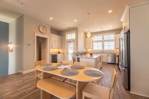 Eine moderne Küche mit Essbereich, Holzboden und Edelstahlgeräten.