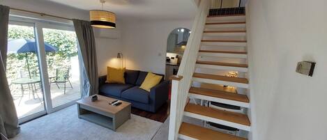 A modern living room with a sofa, coffee table, and a staircase.