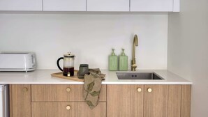 Een keuken met een broodrooster, een koffiezetapparaat en groene zeepdispensers.