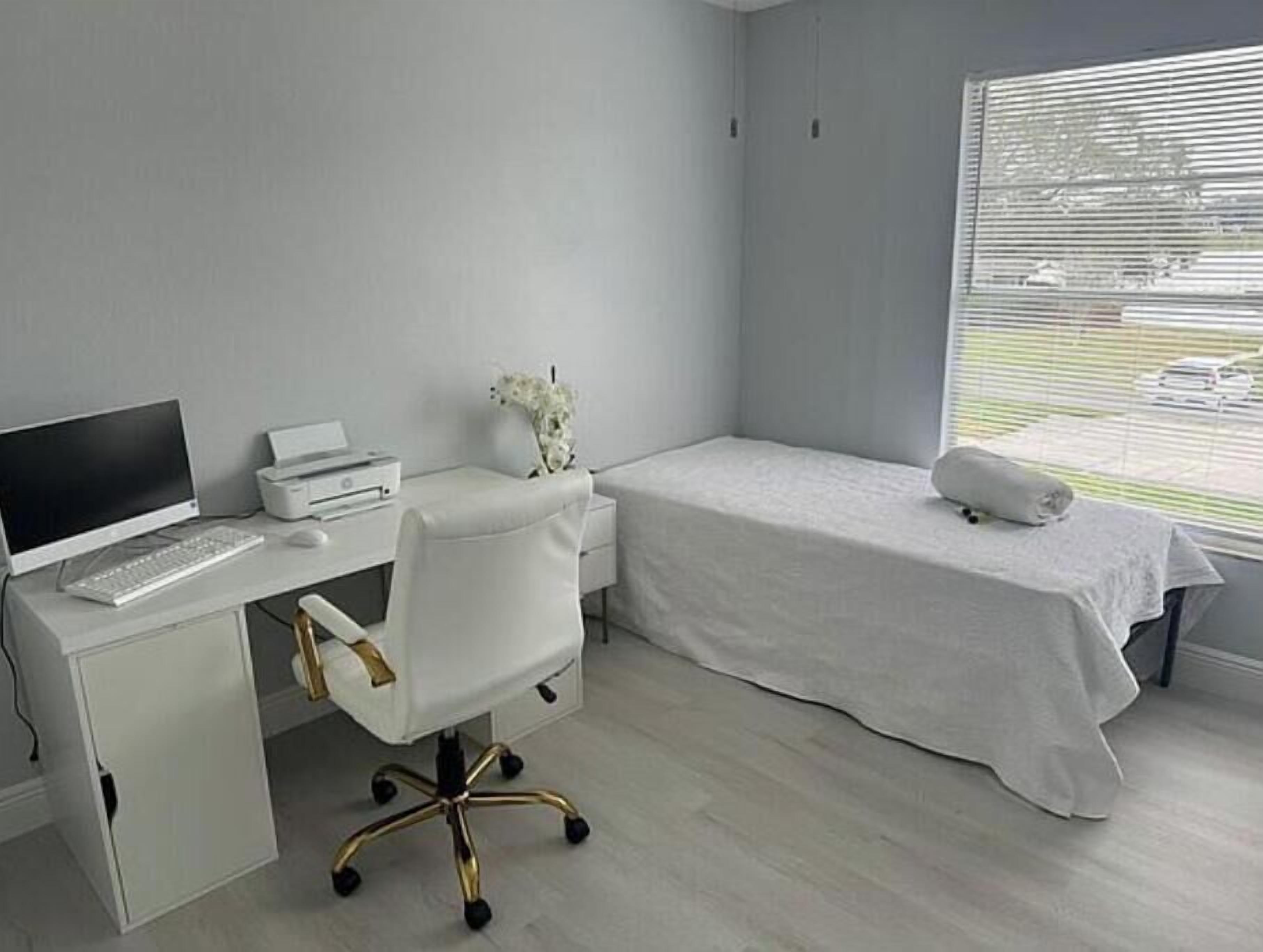 A modern bedroom with a bed, a desk with a computer, and a printer.