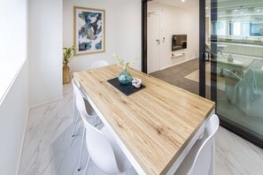 Ein stilvoller Essbereich mit Holztisch, weißen Stühlen, einer Blumenvase und einem Bild an der Wand.