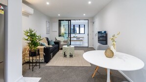 Een moderne woonkamer met een bank, salontafel en een eethoek met een tafel en stoelen.