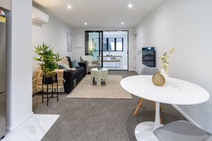 Ein modernes Wohnzimmer mit einer Couch, einem Couchtisch und einem Essbereich mit Tisch und Stühlen.