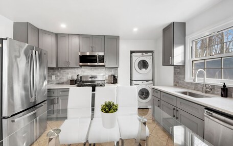 A modern kitchen with stainless steel appliances, a built-in oven, and a washing machine.