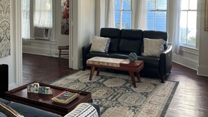 Ein Wohnzimmer mit einem schwarzen Ledersofa, einem Holztisch und einem gemusterten Teppich.