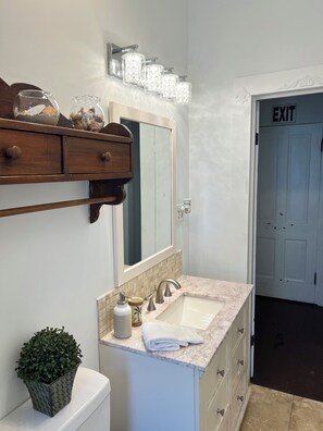 A bathroom with a sink, mirror, vanity, and a potted plant. - Enjoy our newly renovated beautiful Victorian home in downtown St Augustine. (St. Augustine)