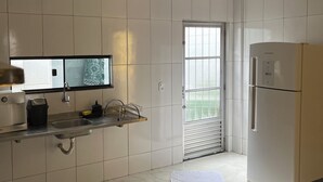 Een moderne keuken met witte tegels, een roestvrijstalen spoelbak, een inbouwoven en een raam met uitzicht.