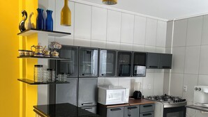 Een moderne keuken met een zwart aanrecht, roestvrijstalen apparatuur en gele wanden.