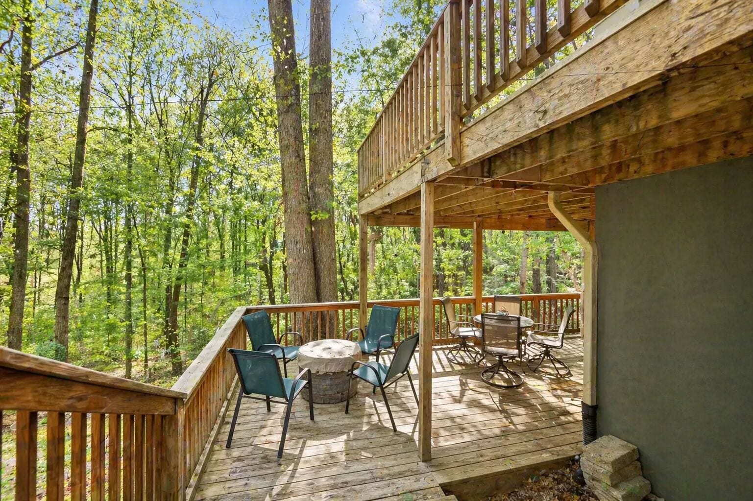 Une terrasse en bois avec des sièges extérieurs et une vue sur une forêt.