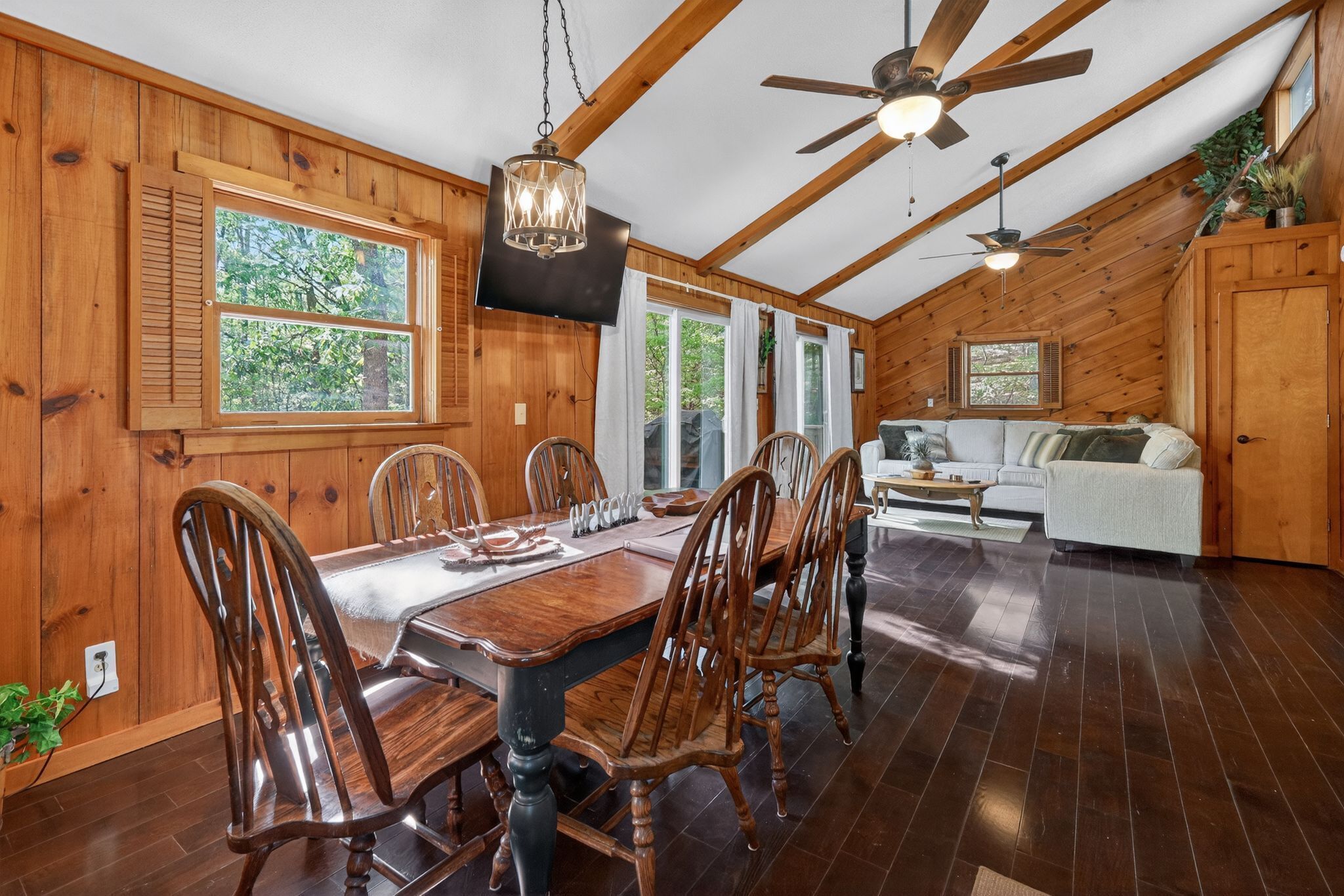 Un intérieur en bois comprenant une table à manger, des chaises, un canapé et des ventilateurs de plafond.