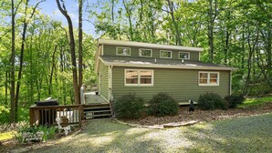A two-story cabin with a front porch, surrounded by trees. - Moneta Memories Lake Retreat | Hot Tub & Fire Pit (Moneta)
