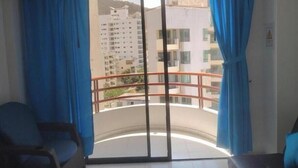 Une pièce dotée d’une porte-fenêtre coulissante donnant sur un balcon agrémenté d’une rambarde en métal.