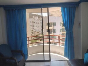 Ein Zimmer mit einer Schiebeglastür, die auf einen Balkon mit Metallgeländer führt.