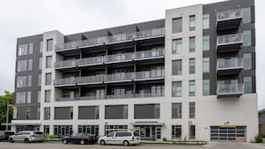 A multi-story residential building with balconies, a parking lot, and a garage. - Walker`s Point Apt with Gym and Balcony | Sleeps 4-5 (Milwaukee)