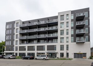 A multi-story residential building with balconies, a parking lot, and a garage. - Walker`s Point Apt with Gym and Balcony | Sleeps 4-5 (Milwaukee)