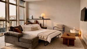 A modern bedroom with a large bed, a sofa, a chair, a desk, and a TV. - Walker`s Point Apt with Gym and Balcony | Sleeps 4-5 (Milwaukee)