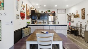 Een moderne keuken met donkere kastjes, een roestvrijstalen koelkast en een houten eettafel met een witte stoel.